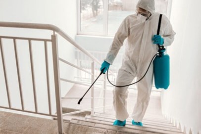 Operario con traje de protección desinfectando una escalera con un pulverizador